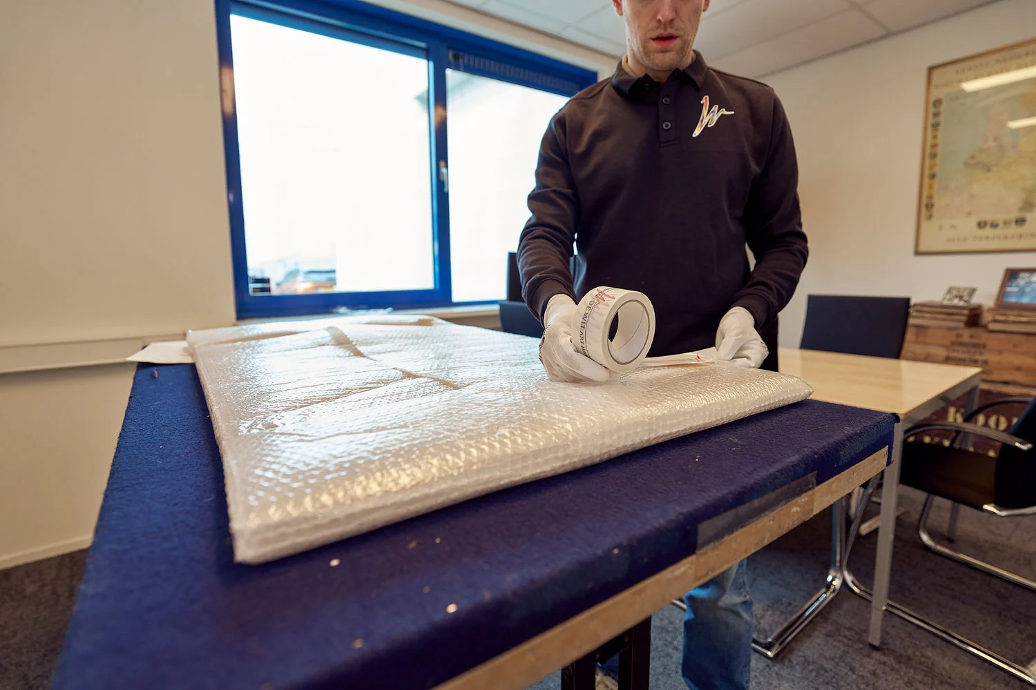 Medewerker van De Wit Art Handling verpakt een kunstwerk aan de werktafel
